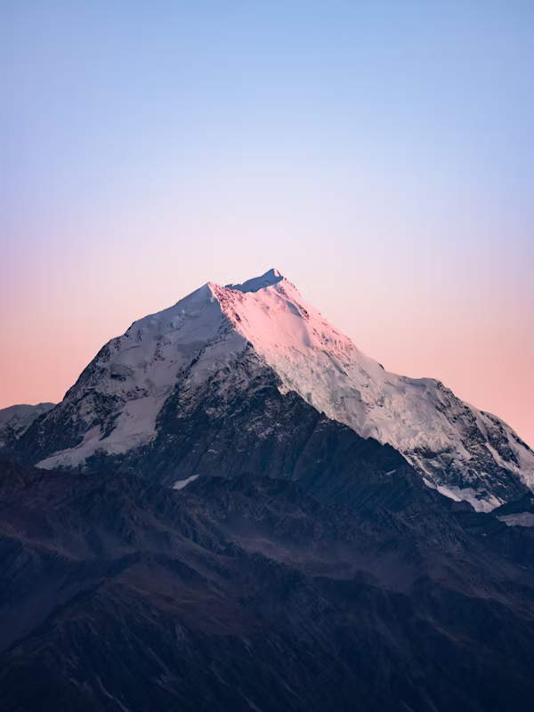 A mountain at dusk with a pink glow on it